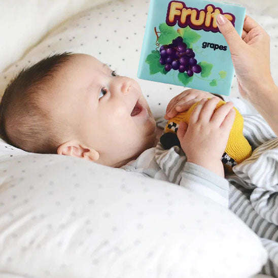 nourrisson regarde livre pour bebe en tissu fruits