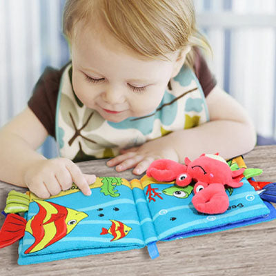 nourrisson touche livre bebe avec crabe