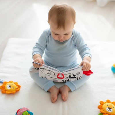 enfant assis regarde livre bebe en tissus marins